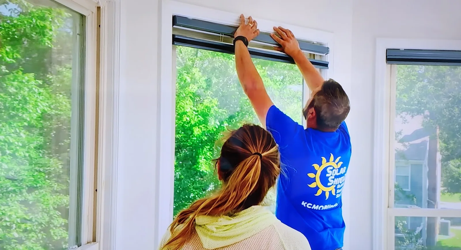 A Solar Shield Blinds installer fitting a shade while the homeowner looks on