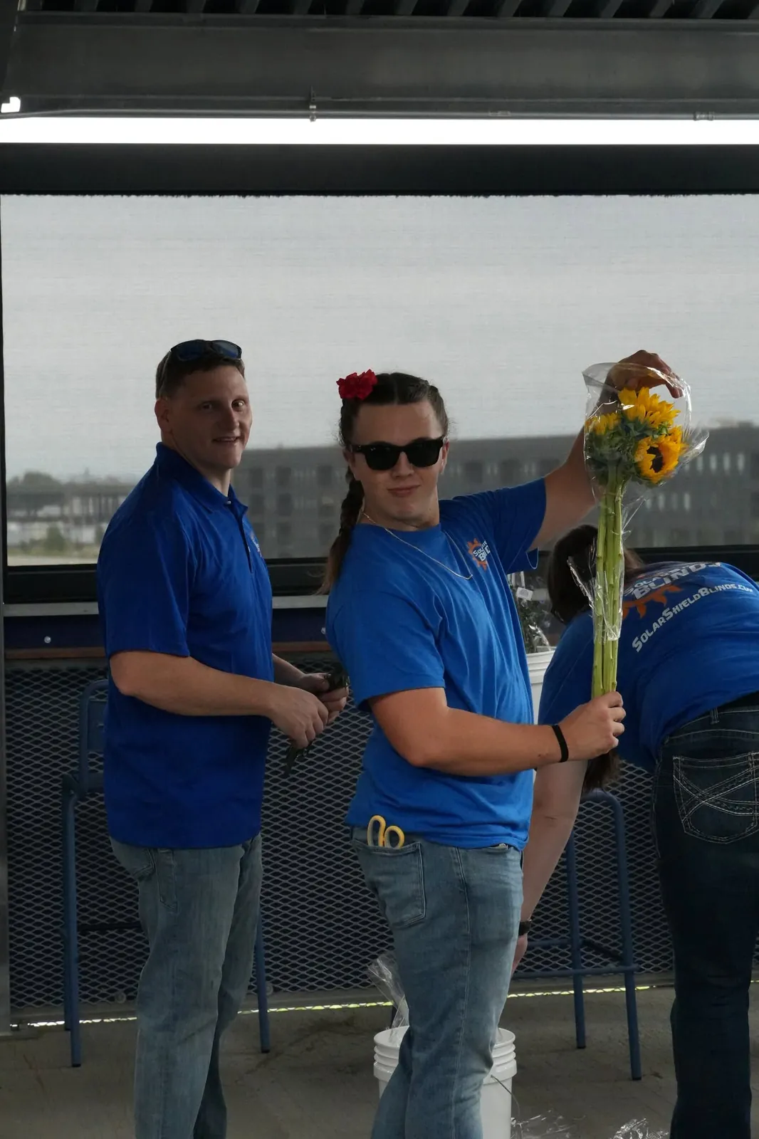 Two team members with a sunflower bouquet at an outdoor event