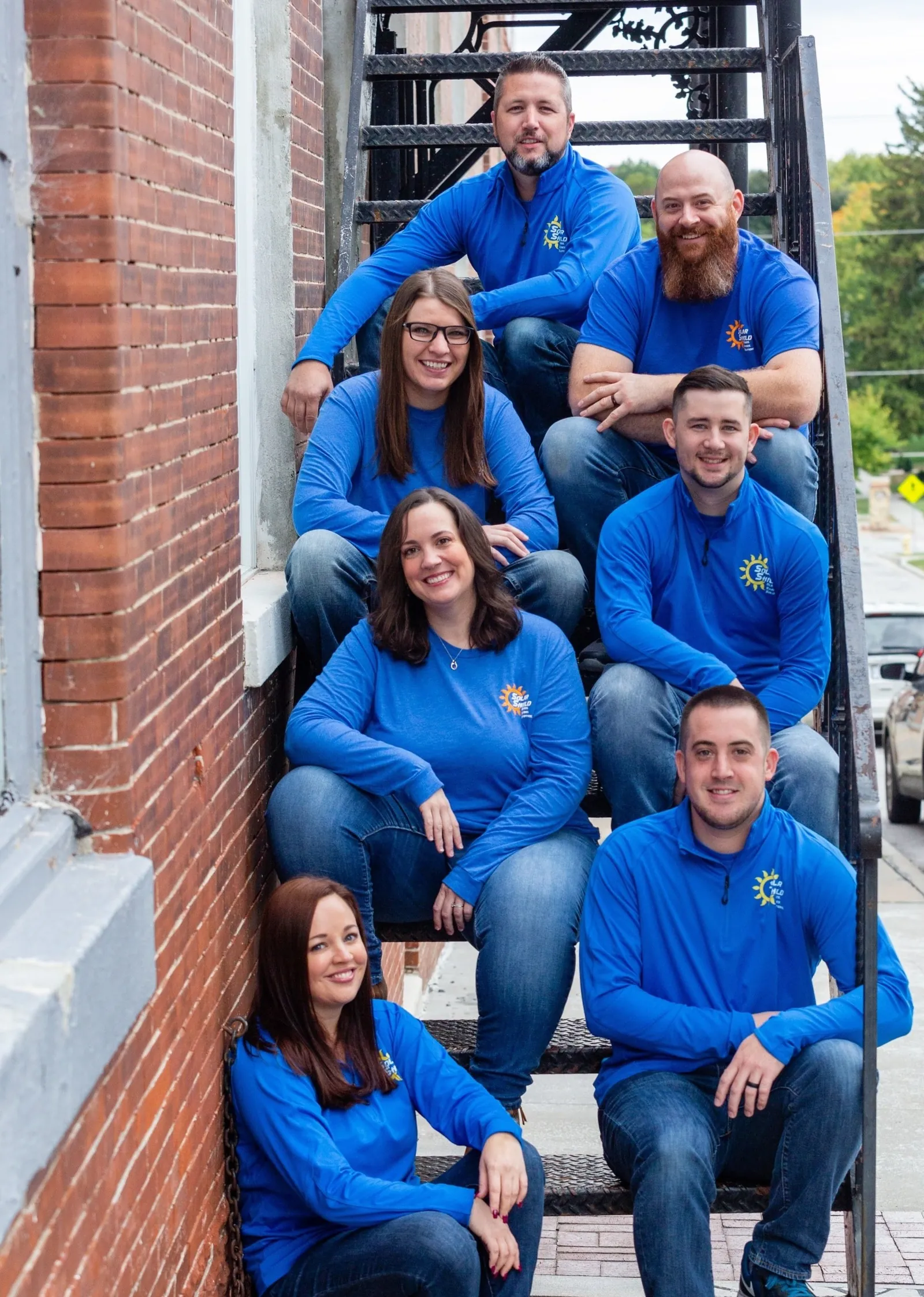 The Solar Shield Blinds team seated on a set of outdoor stairs