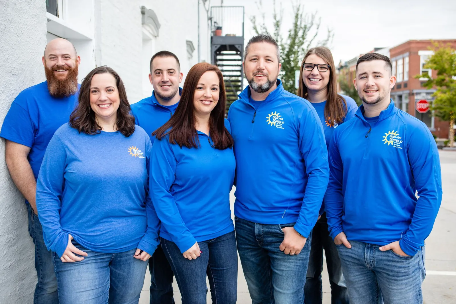 The Solar Shield Blinds team in blue company shirts on a downtown street