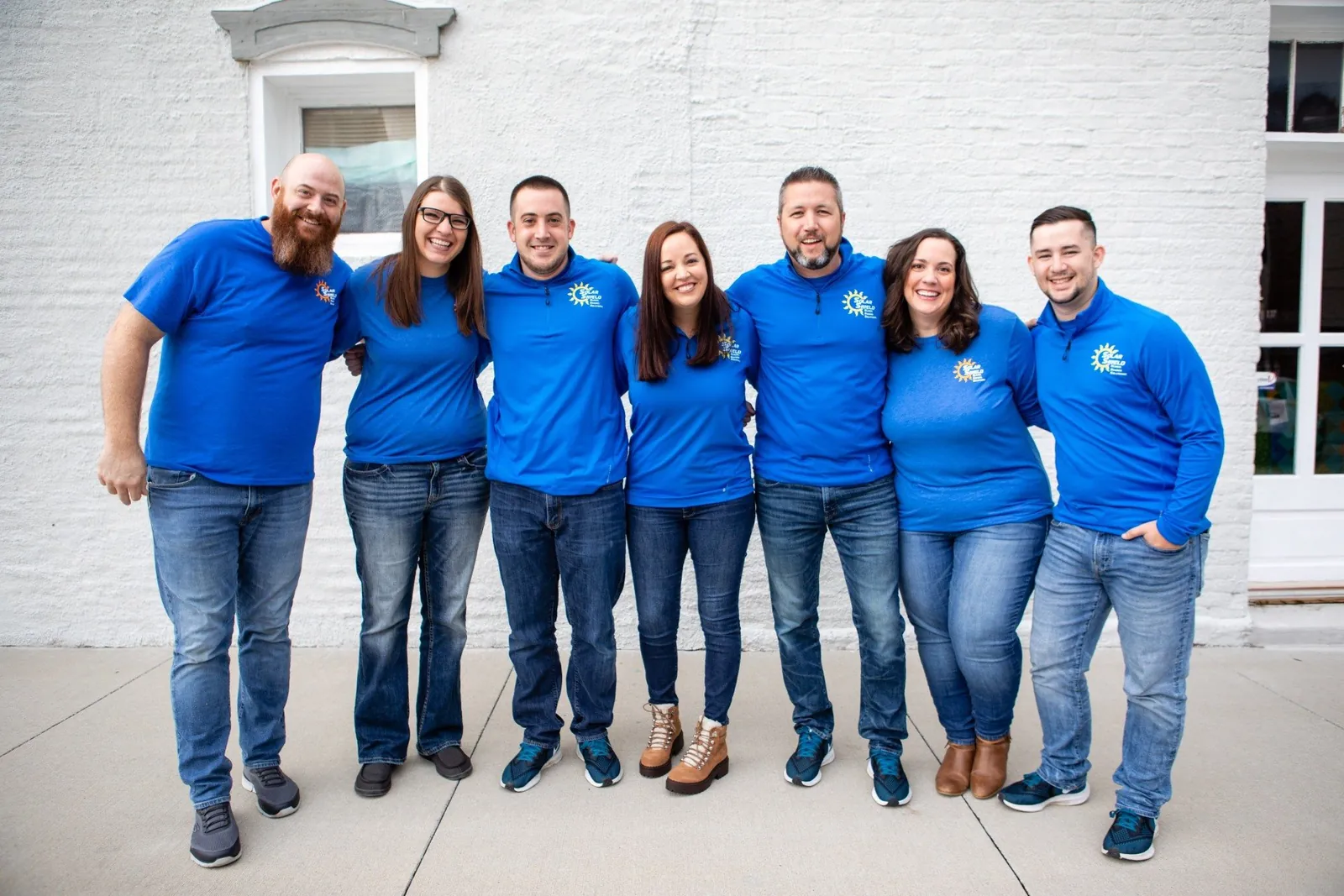The Solar Shield Blinds team in front of a white brick wall
