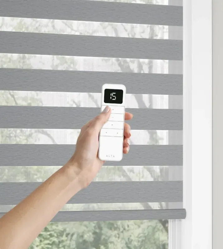 A hand using the remote control to lower a motorized shade