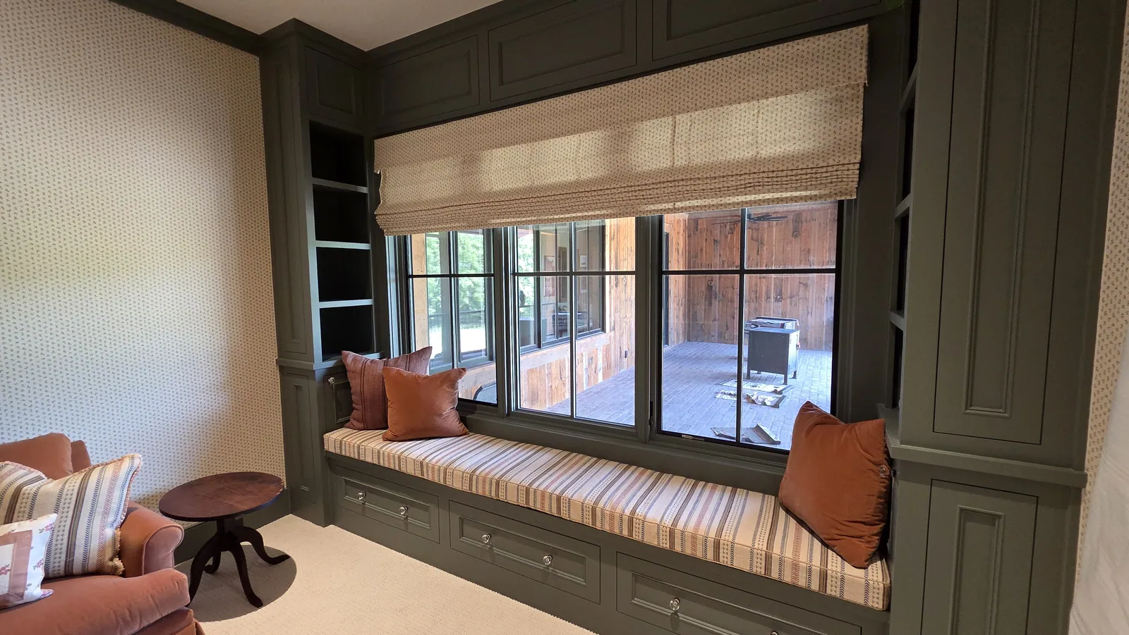 A striped window seat cushion under a Natural Woven Shade, installed by Solar Shield Blinds