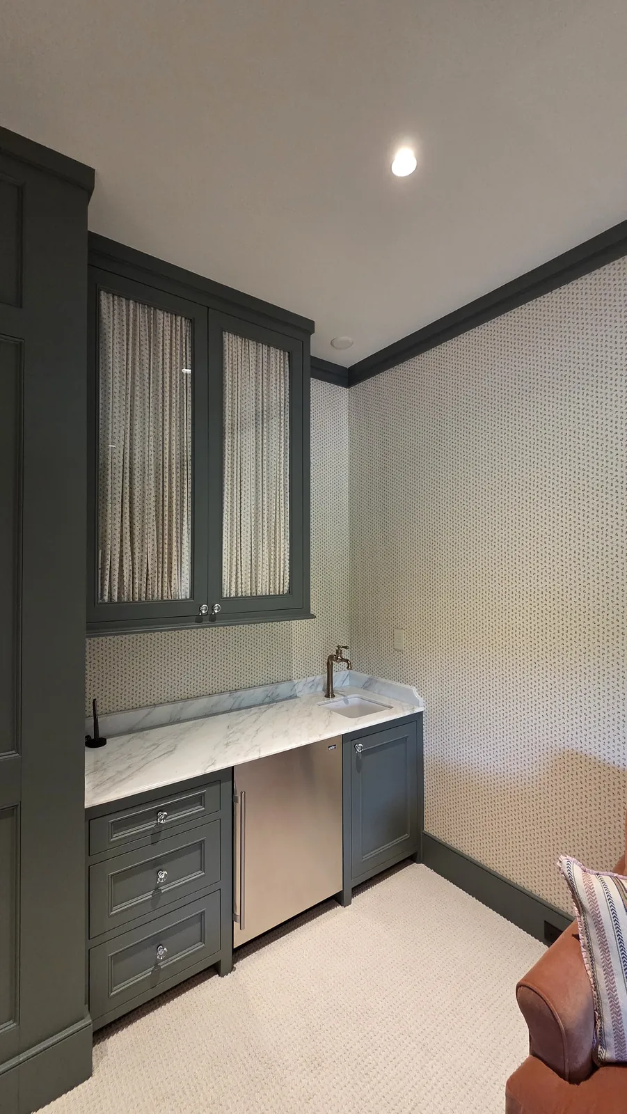Green bar cabinetry with curtains behind its glass doors, installed by Solar Shield Blinds