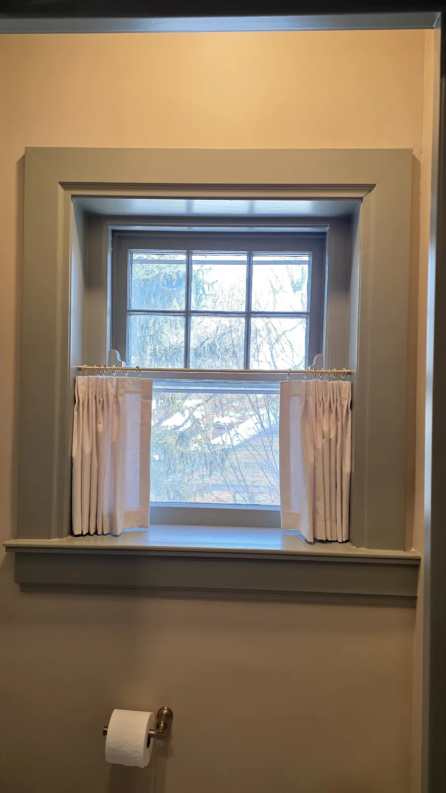 A pleated café curtain across the lower half of a small bathroom window, installed by Solar Shield Blinds