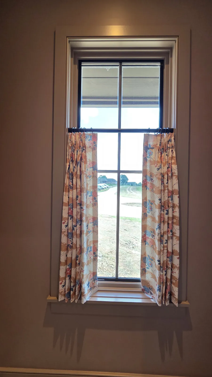 Floral café curtains on a tall window with dark trim, installed by Solar Shield Blinds