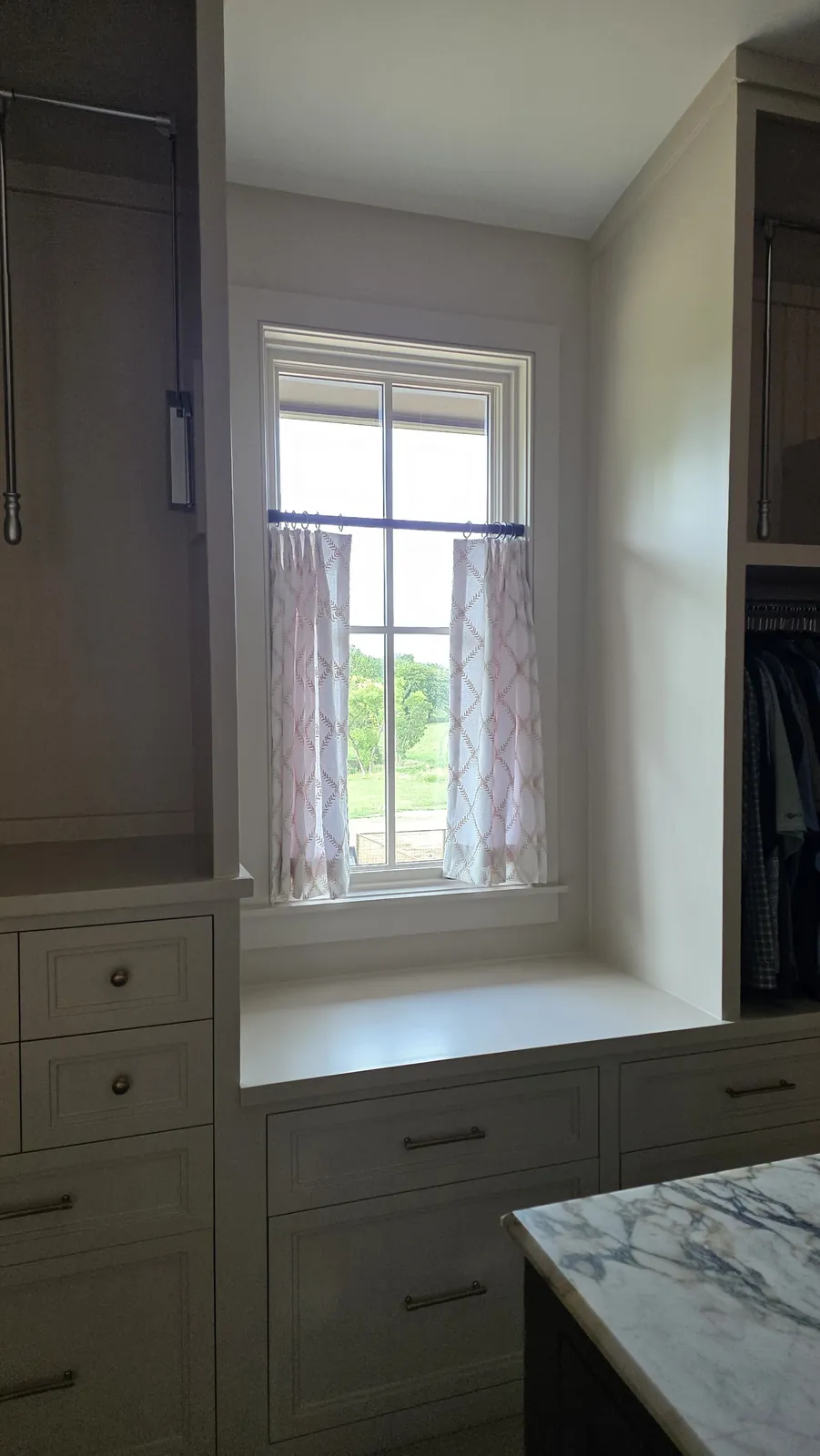 Café curtains on a window above a built in seat in a dressing room, installed by Solar Shield Blinds