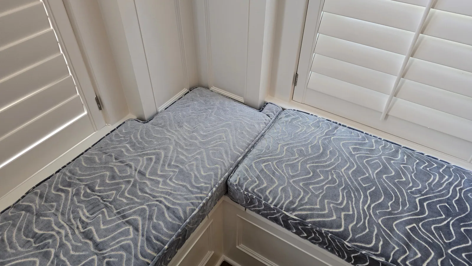 Custom banquette cushions in a corner seat, installed by Solar Shield Blinds