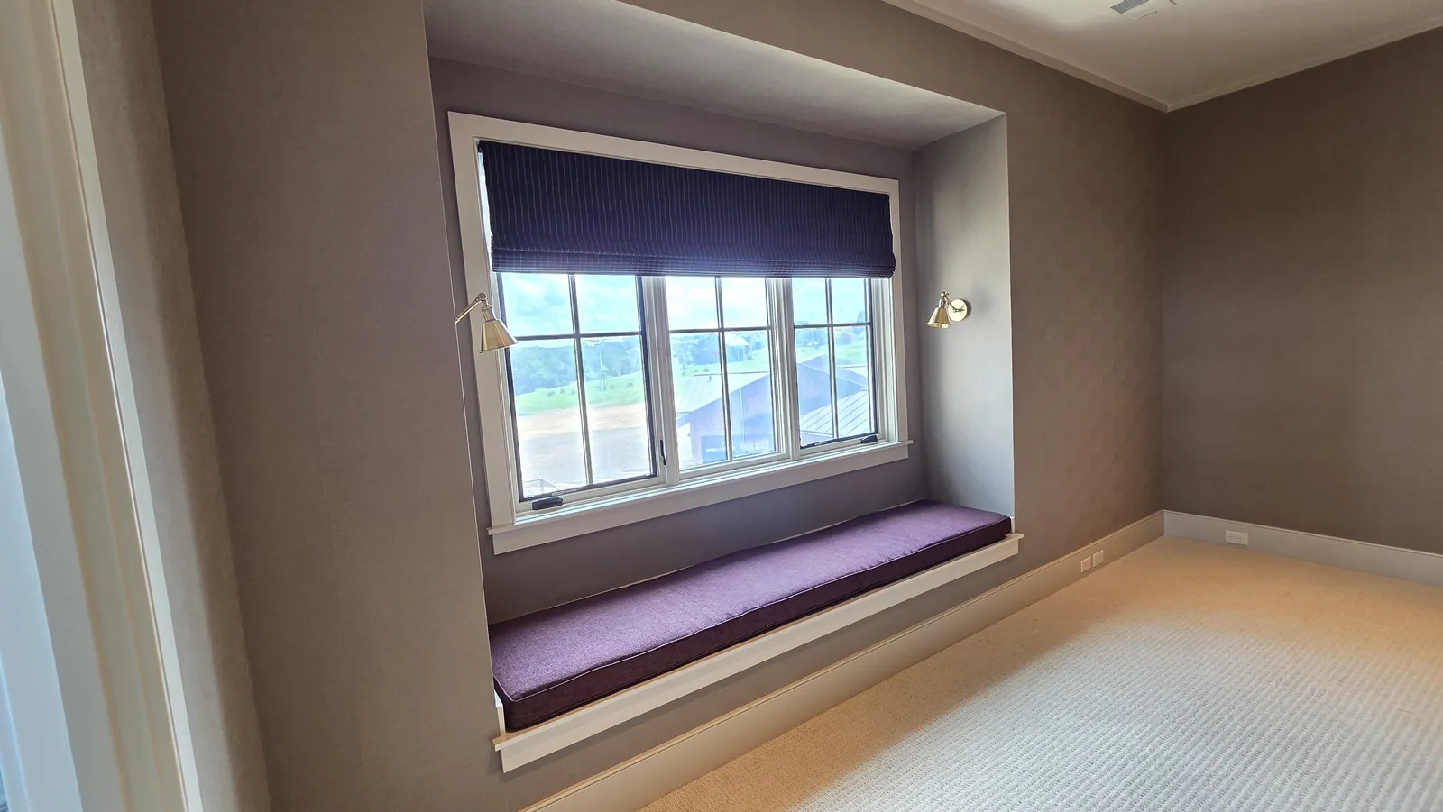 A window seat cushion under a Roman shade, installed by Solar Shield Blinds