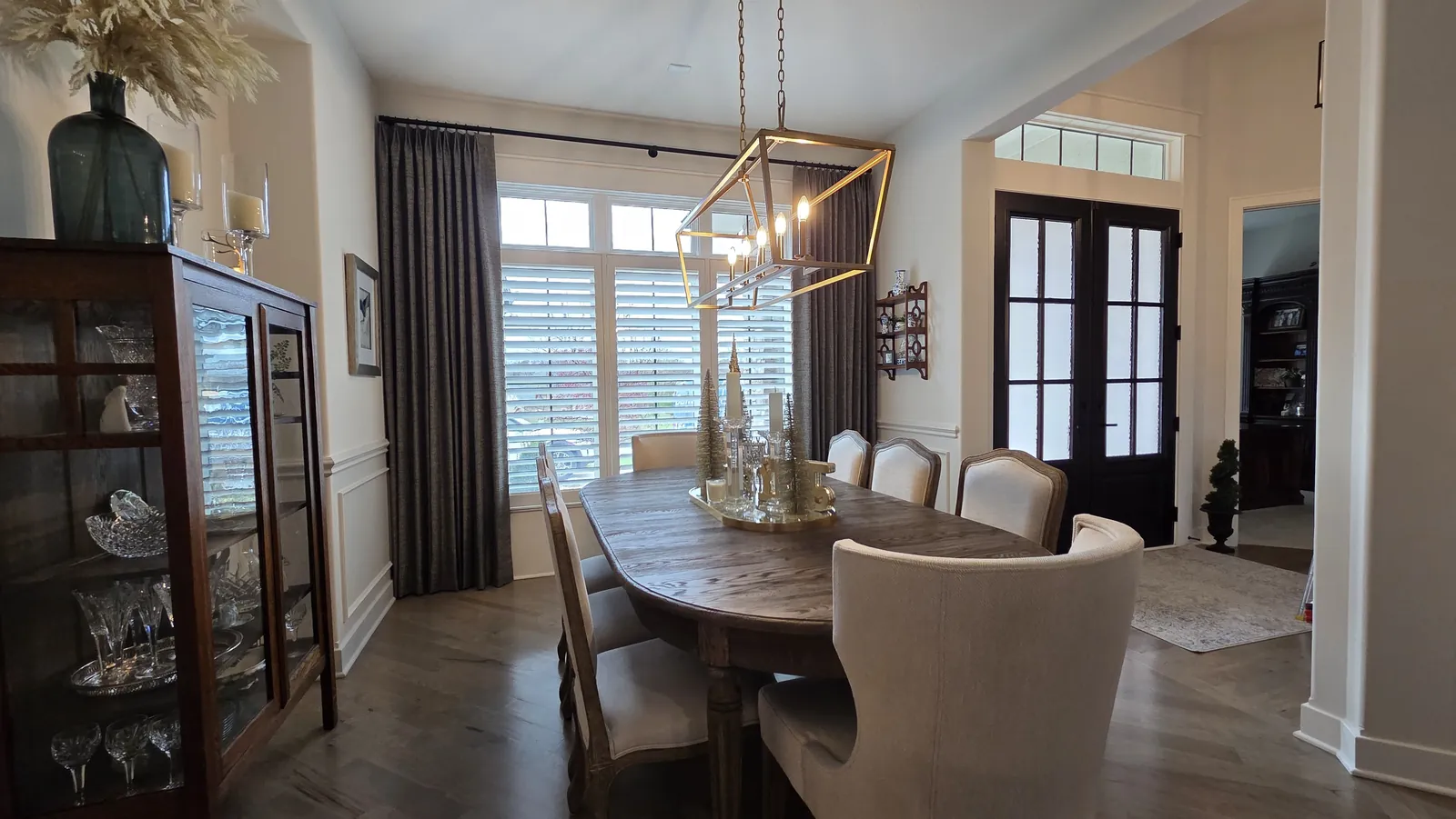 Dark drapery panels on the windows of a dining room, installed by Solar Shield Blinds