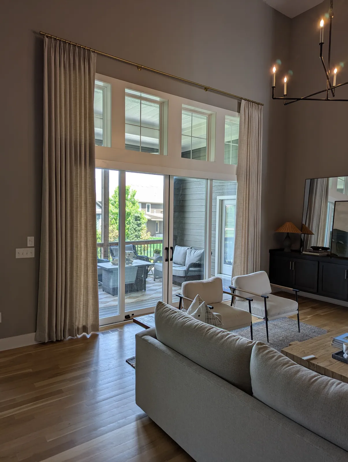 Floor to ceiling drapery panels on a two story wall of windows and a sliding door, installed by Solar Shield Blinds