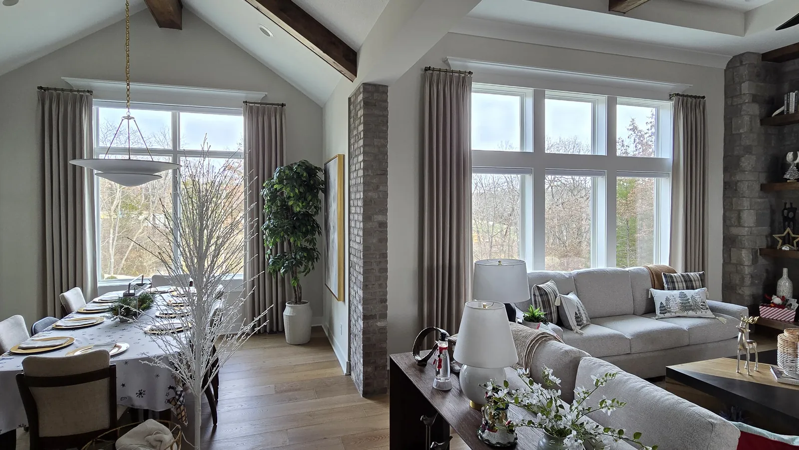 Drapery panels on the tall windows of an open dining and living room, installed by Solar Shield Blinds