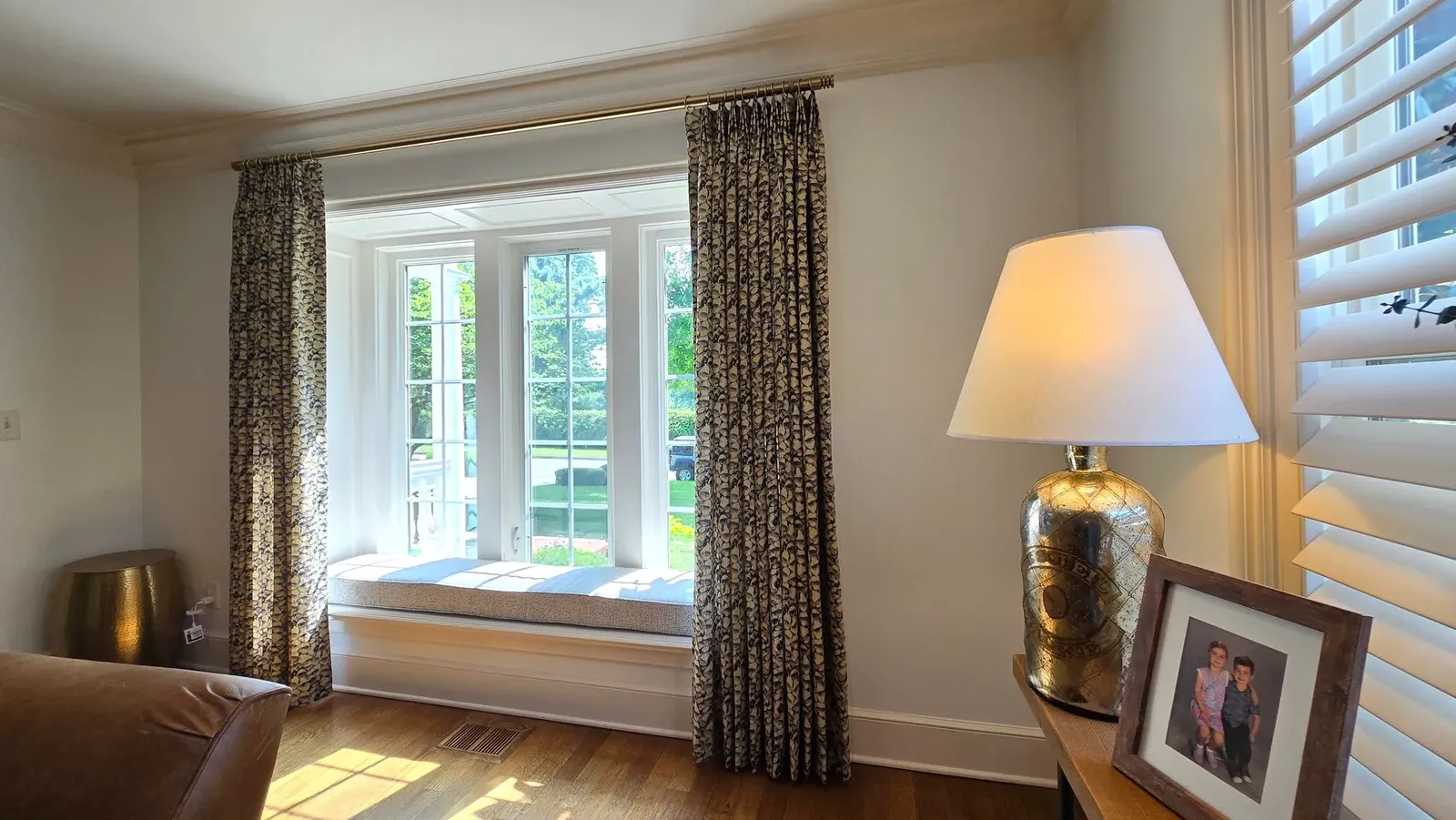 Window seat cushion framed by drapery panels, installed by Solar Shield Blinds