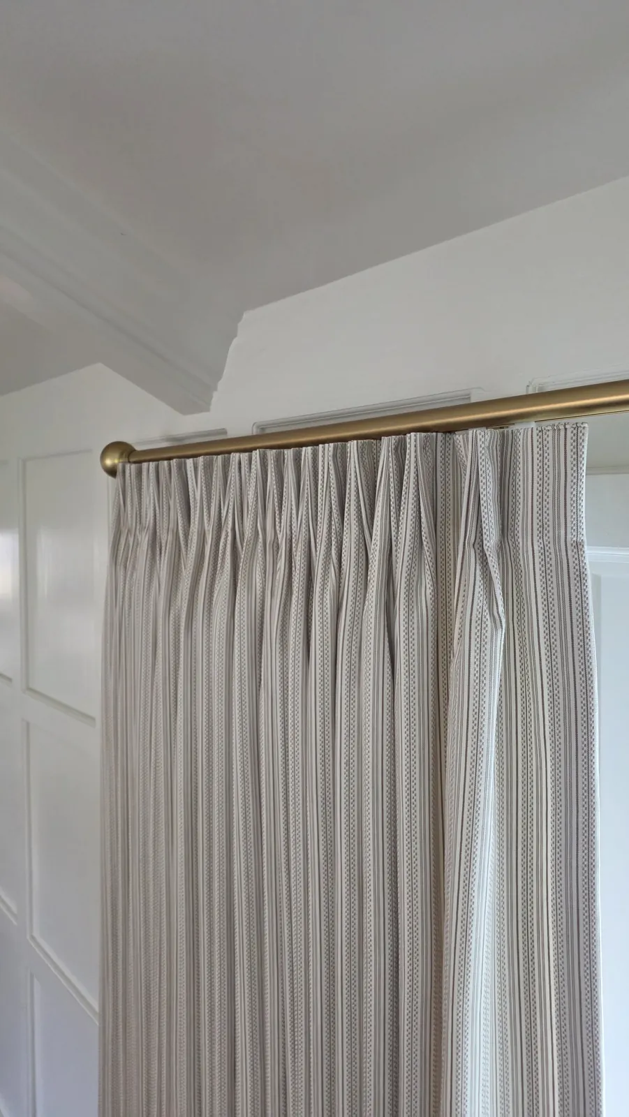 Close up of a pinch pleat drapery header on a brass rod, installed by Solar Shield Blinds