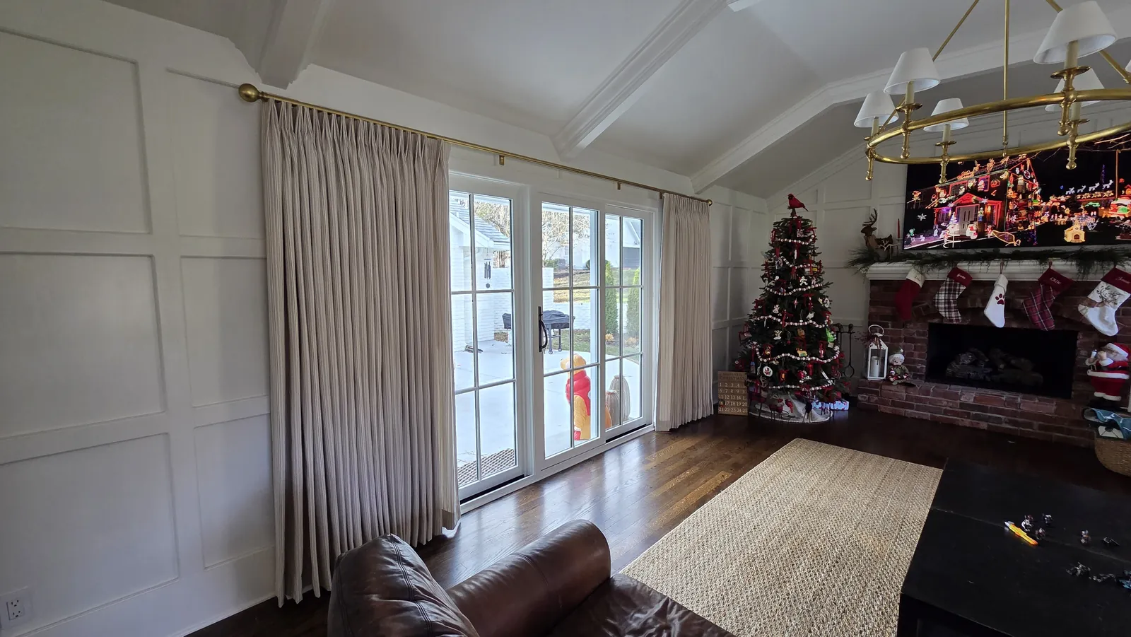 Pinch pleat drapery over the French doors of a paneled living room, installed by Solar Shield Blinds