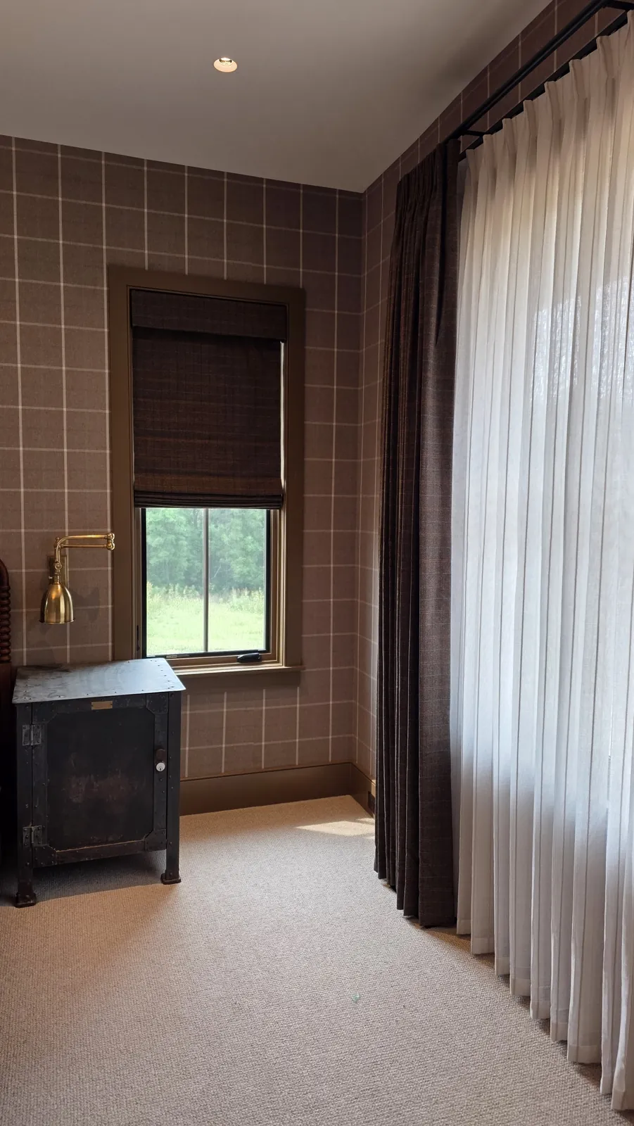 Sheer drapery and a Roman shade in a bedroom with plaid wallpaper, installed by Solar Shield Blinds