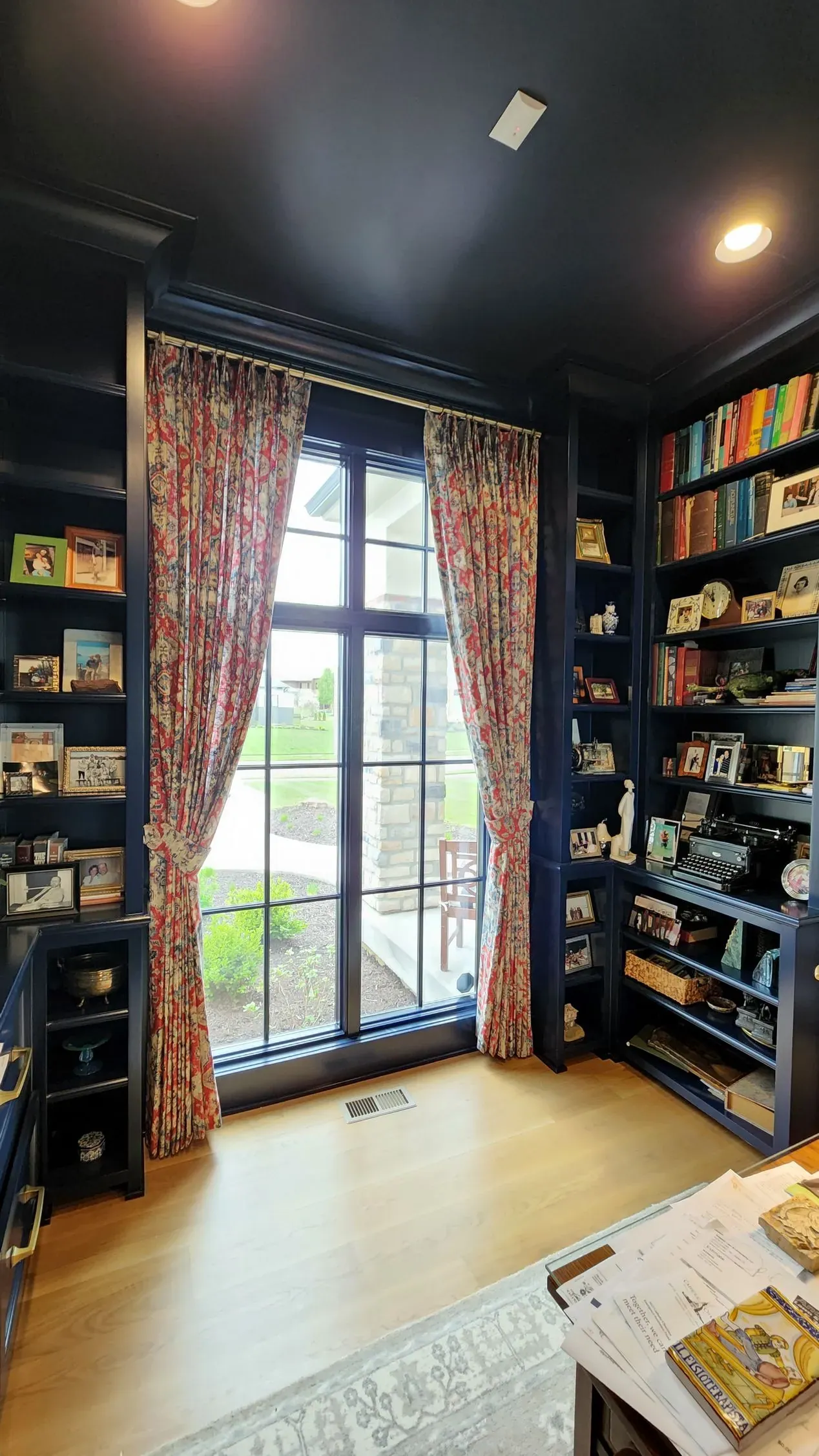 Floral drapery panels in a home library, installed by Solar Shield Blinds