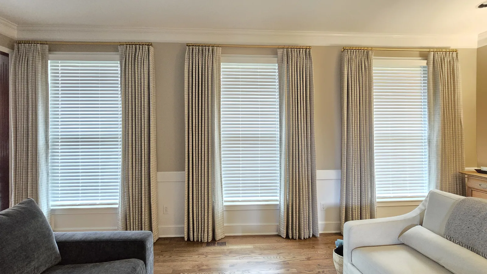 Drapery panels between living room windows, installed by Solar Shield Blinds