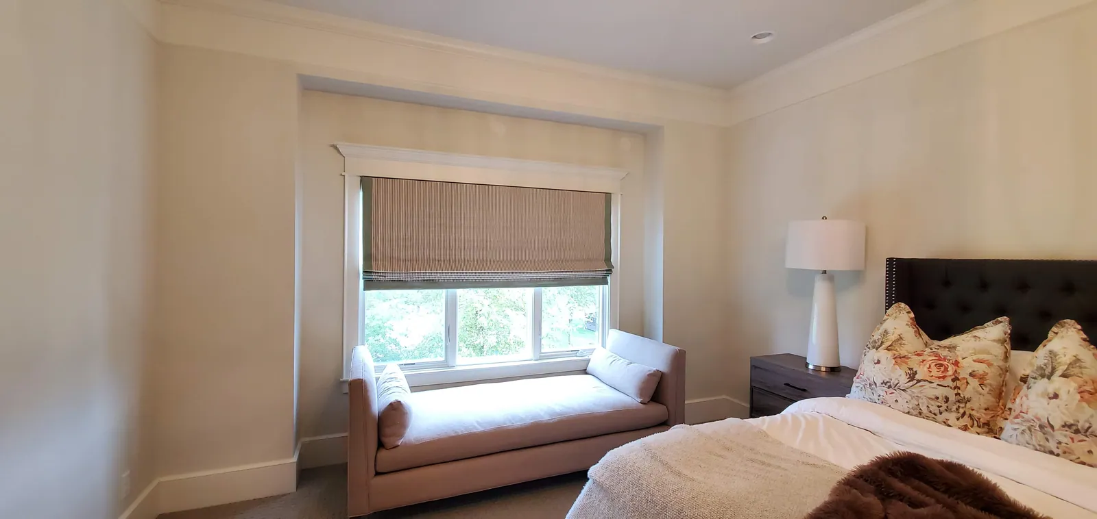 Roman shade over a bedroom window seat, installed by Solar Shield Blinds