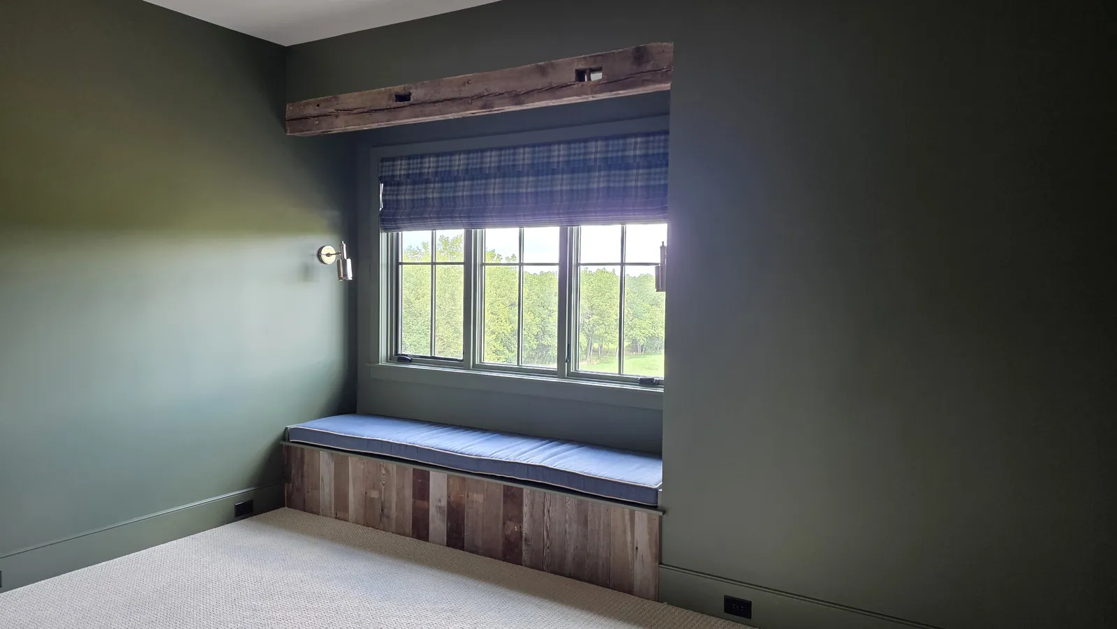 A window seat cushion in a bay with a reclaimed wood front, installed by Solar Shield Blinds