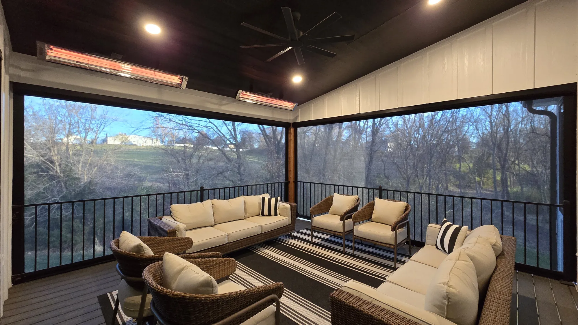 Exterior Patio Shades around a covered patio with overhead heaters and wicker seating, installed by Solar Shield Blinds