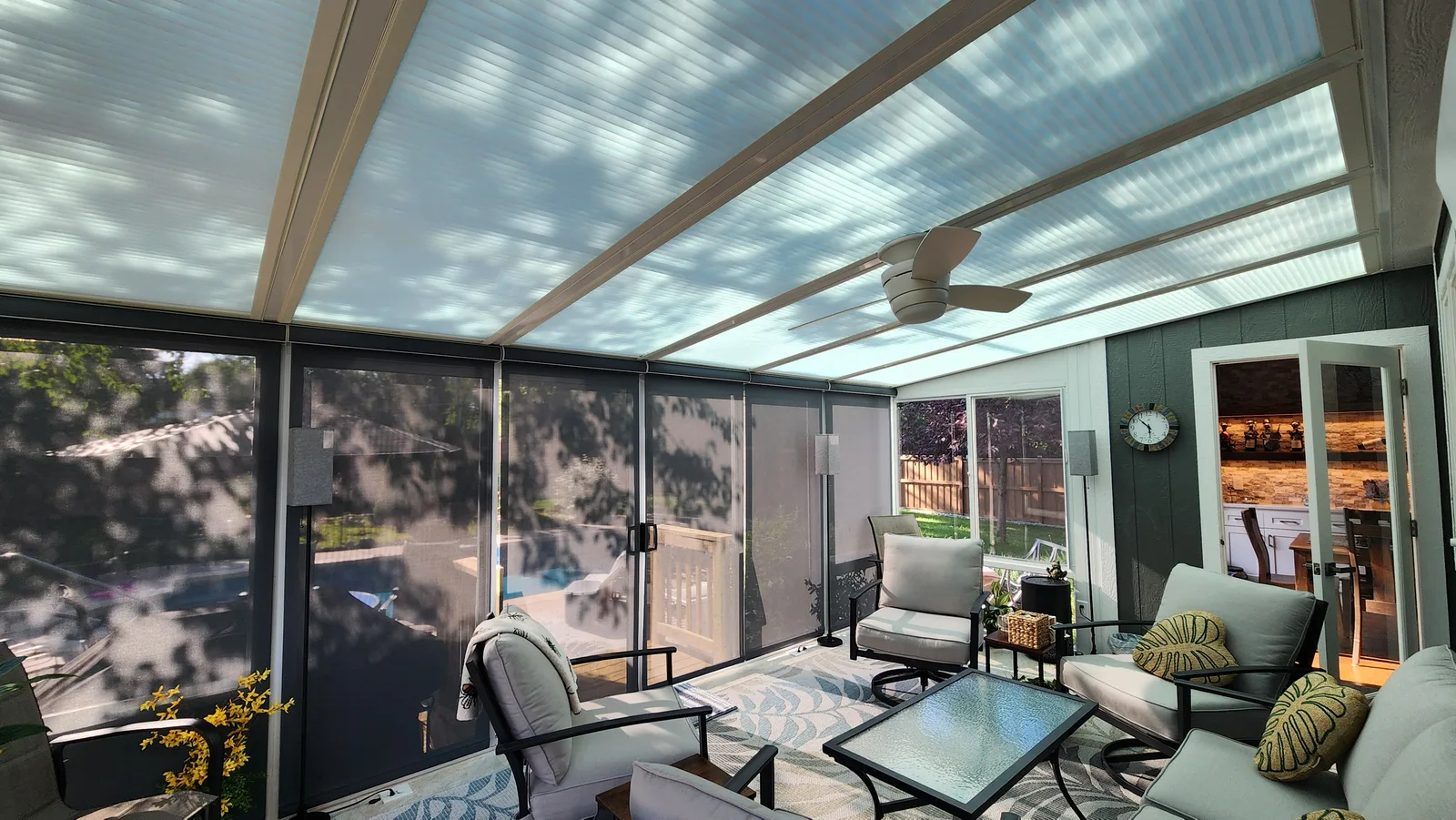 A covered patio enclosed with motorized exterior screens, looking out over the garden