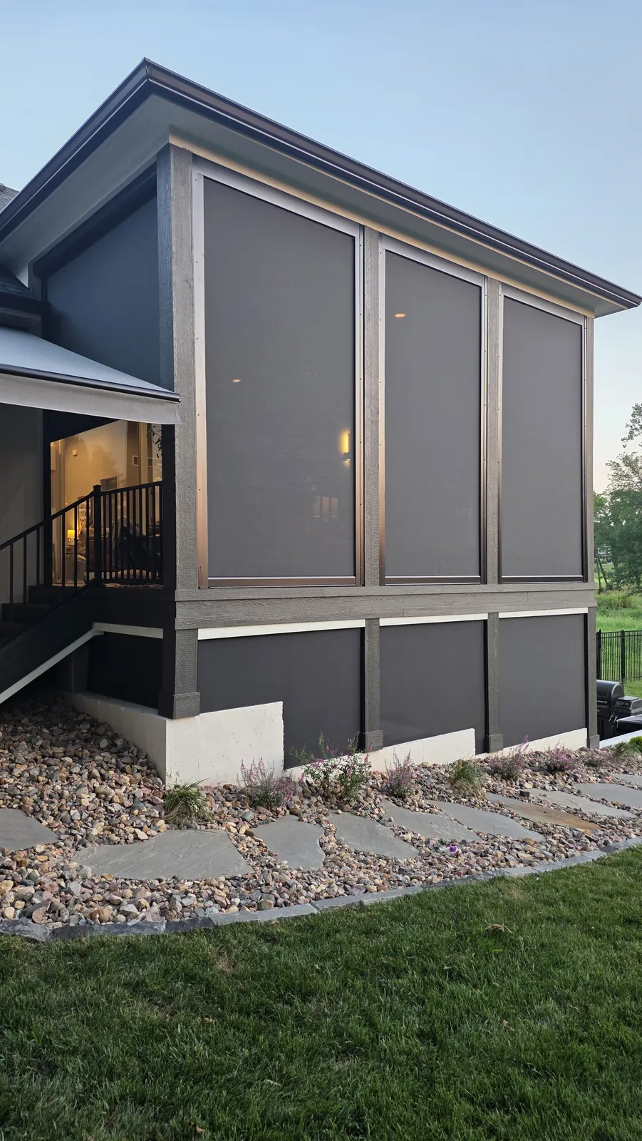A screened porch on a deck in the evening light, seen from the side yard