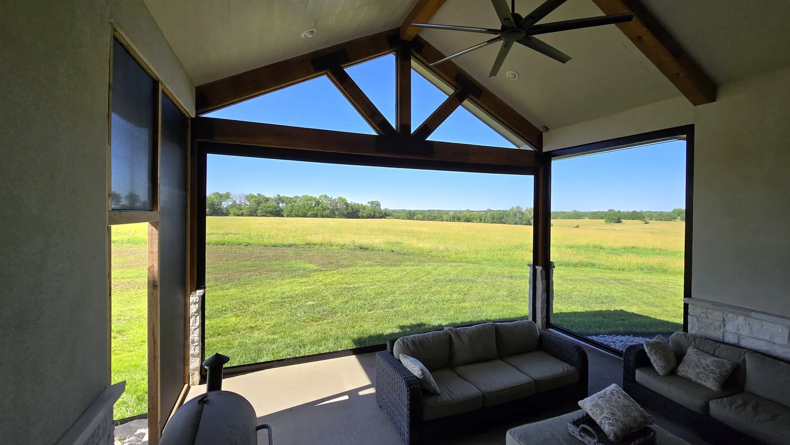 Looking out from a screened porch under a gable to an open field