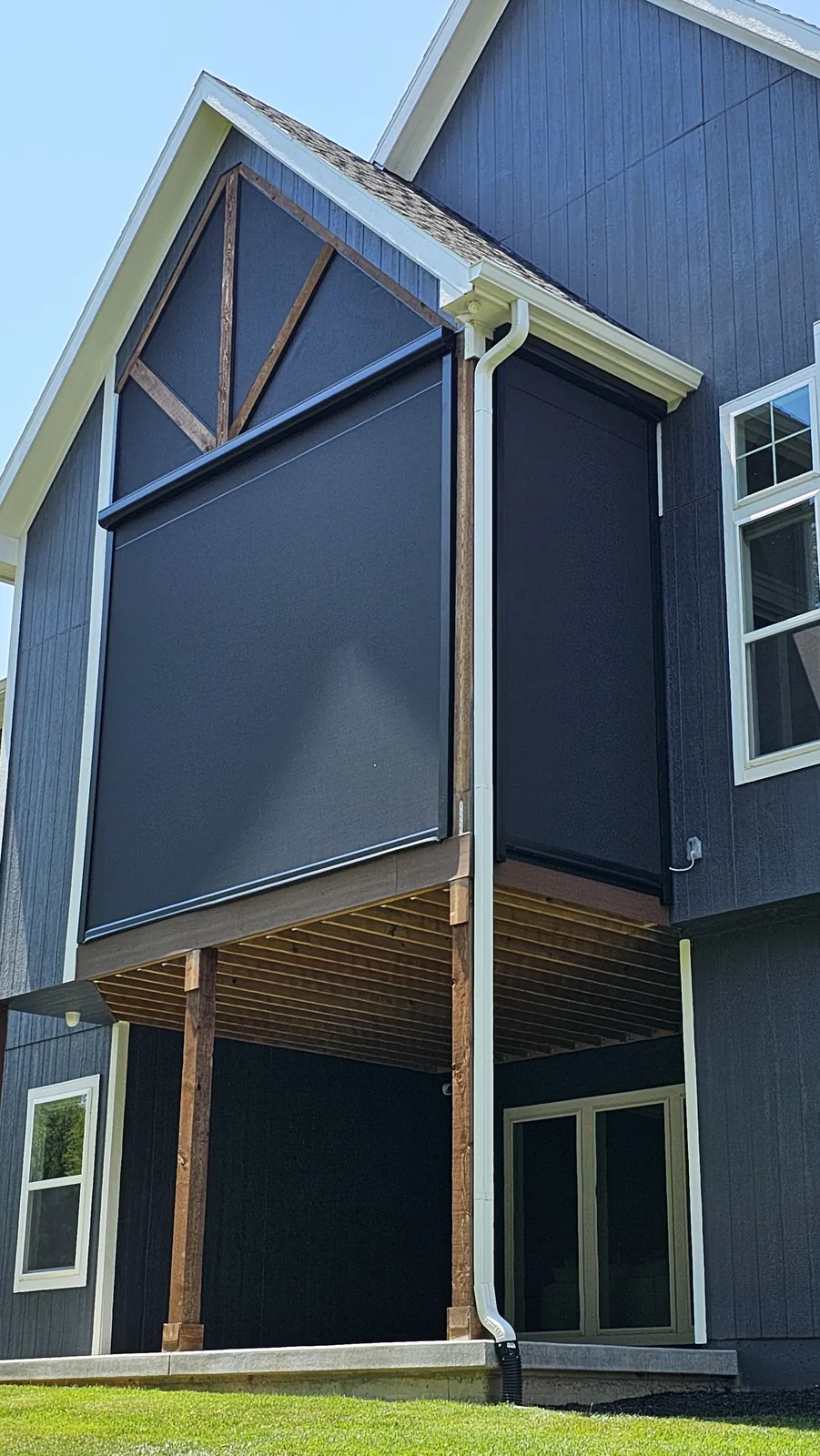 An upper deck under a gable roof on a dark gray home, screened in to the peak