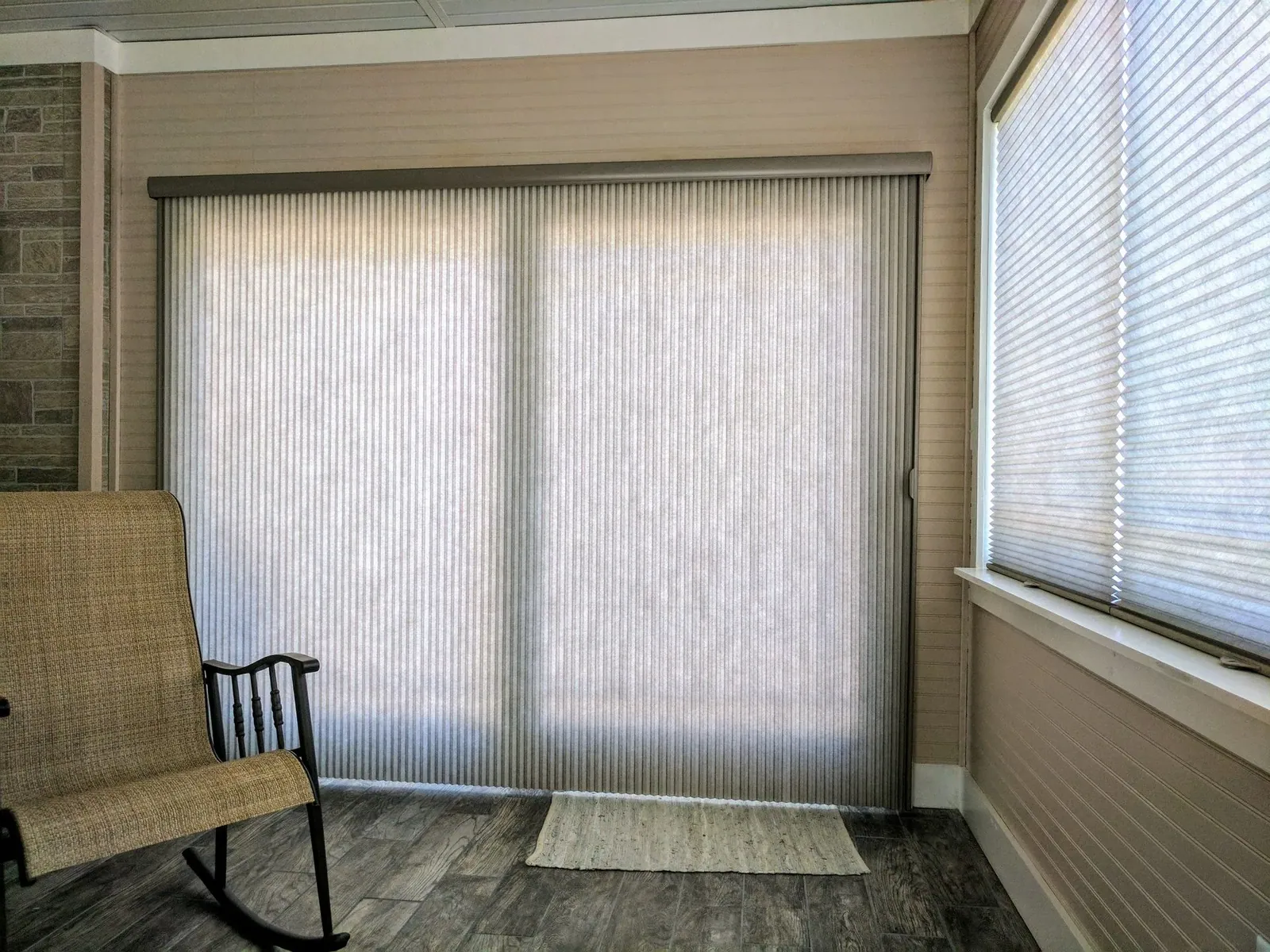 Vertical honeycomb shade and standard honeycomb shades closed over a sunroom sliding patio door and side windows, installed by Solar Shield Blinds