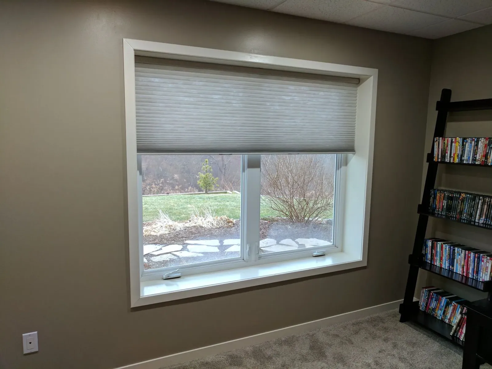 Honeycomb shade half opened on a lower family room window, installed by Solar Shield Blinds
