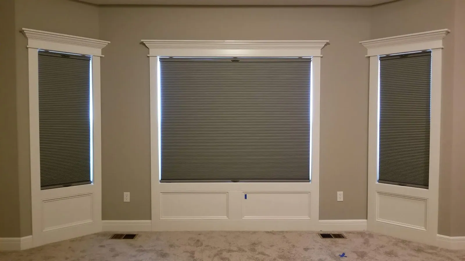 Honeycomb shades closed on three living room windows