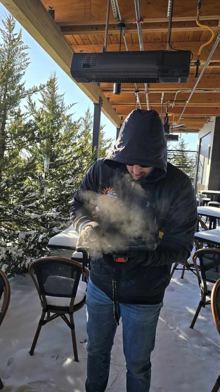 A Solar Shield Blinds specialist in winter gear measuring the snow covered Meddy's patio