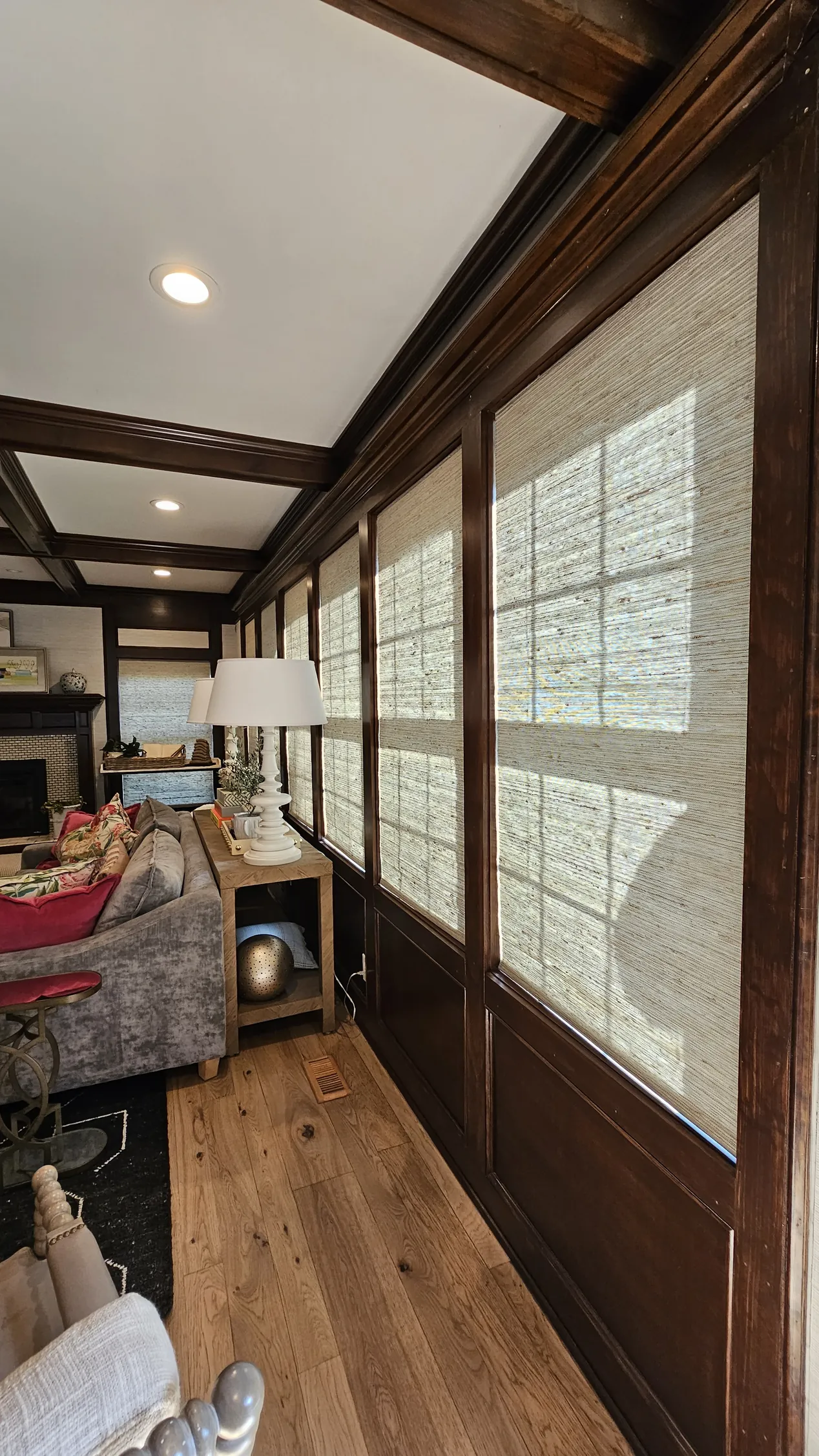 Natural Woven Shades down a paneled living room wall, a Solar Shield Blinds install