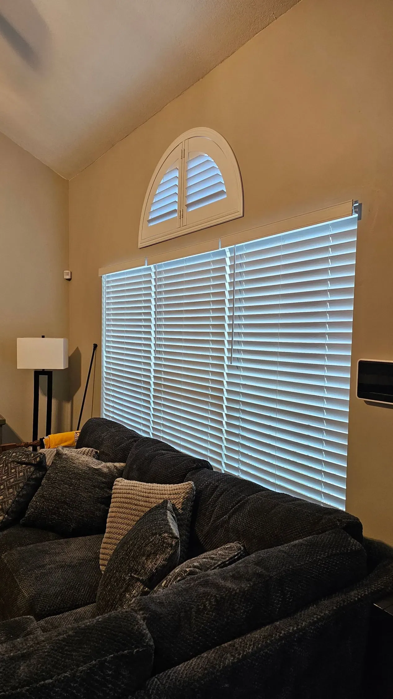 Plantation Shutters arched in a living room, a Solar Shield Blinds install