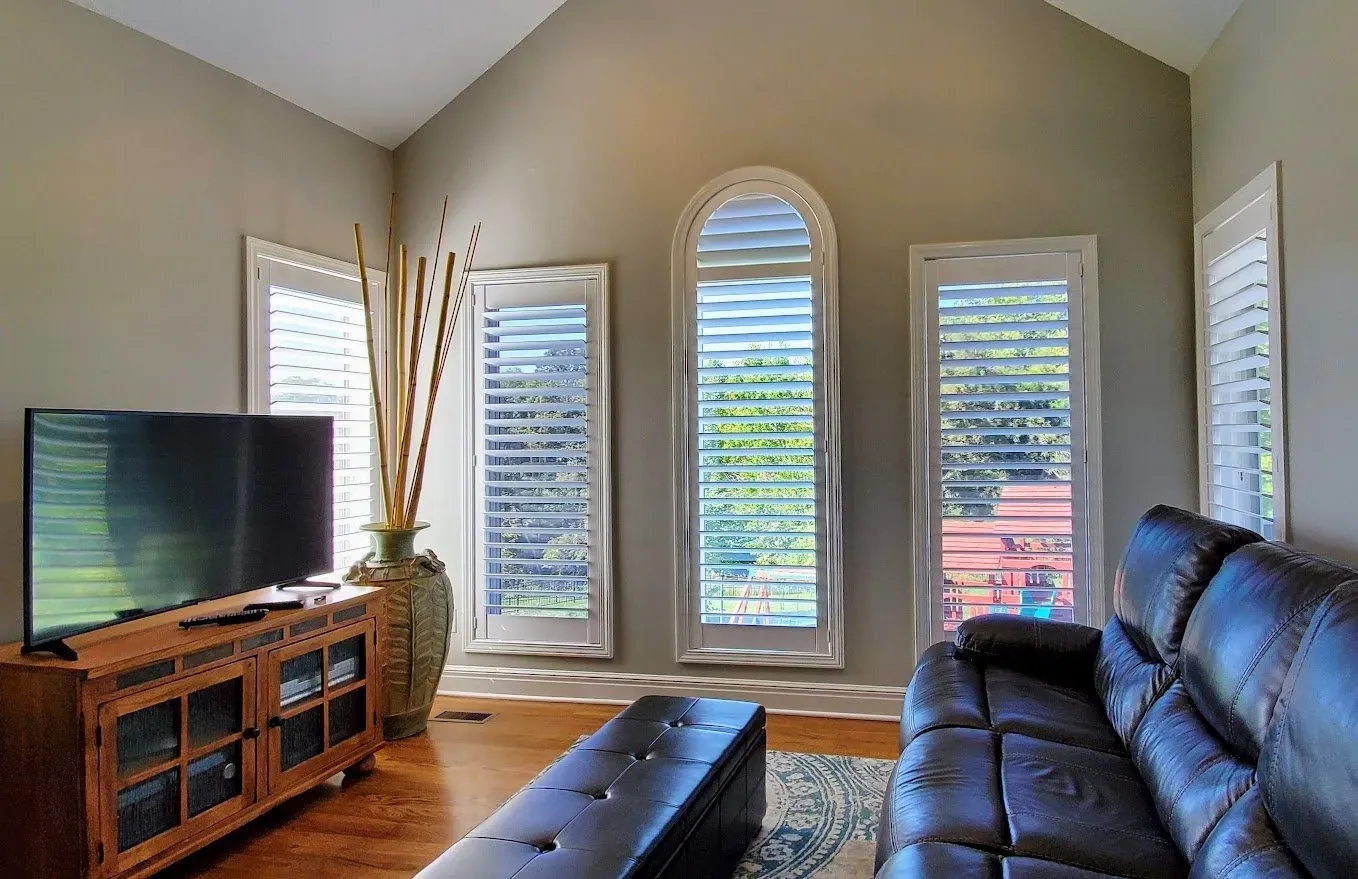 Plantation Shutters arched in a living room, a Solar Shield Blinds install