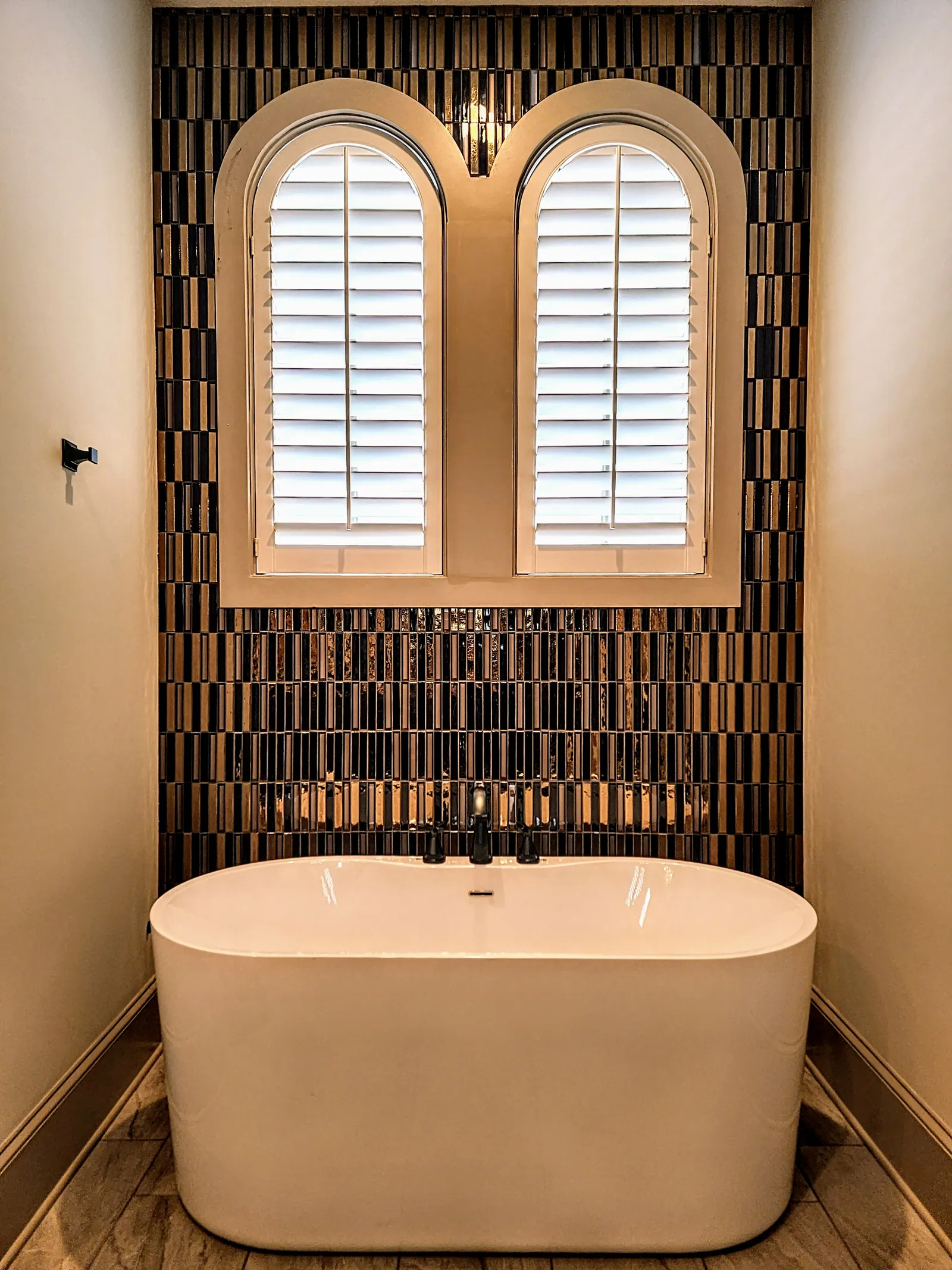 Custom plantation shutters arched speciality shape above tub in, installed by Solar Shield Blinds