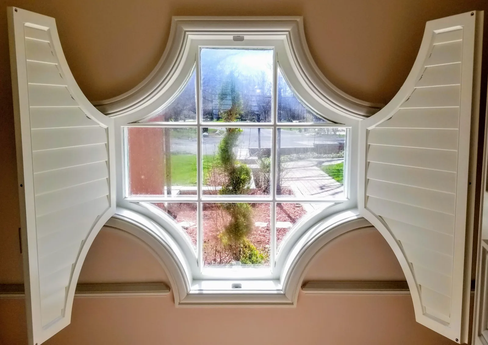 Plantation shutters templated to a handcrafted cross-pattern arched window