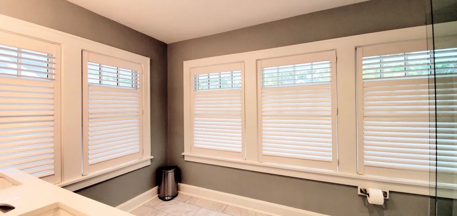 Plantation Shutters half open in room, a Solar Shield Blinds install