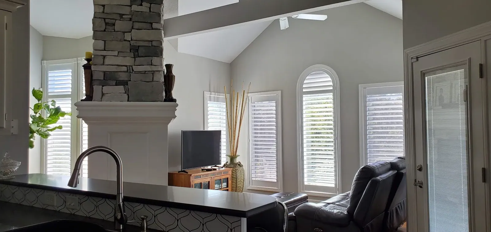 Open arched plantation shutters in living room, installed by Solar Shield Blinds