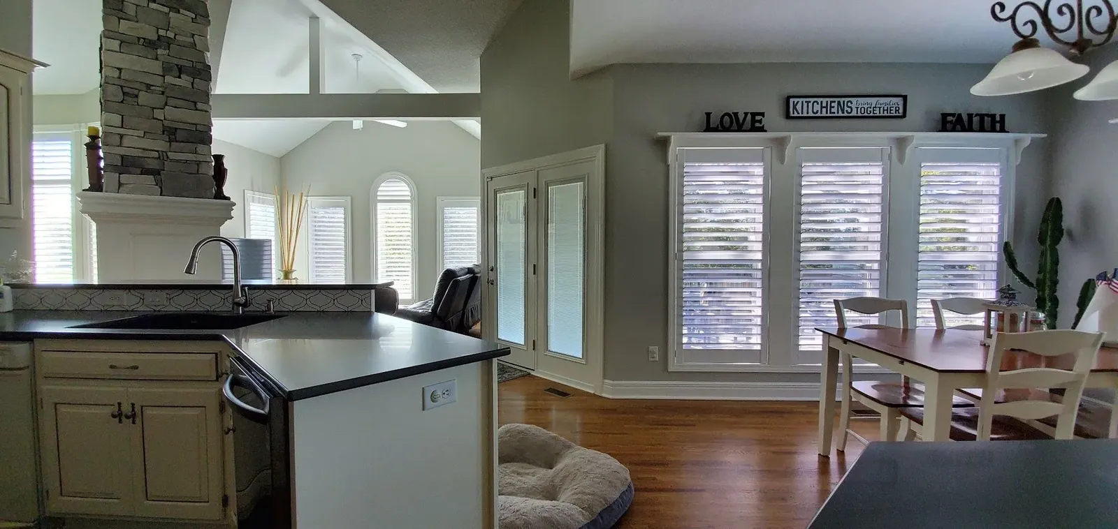 Plantation shutters across an open concept kitchen and dining area, installed by Solar Shield Blinds