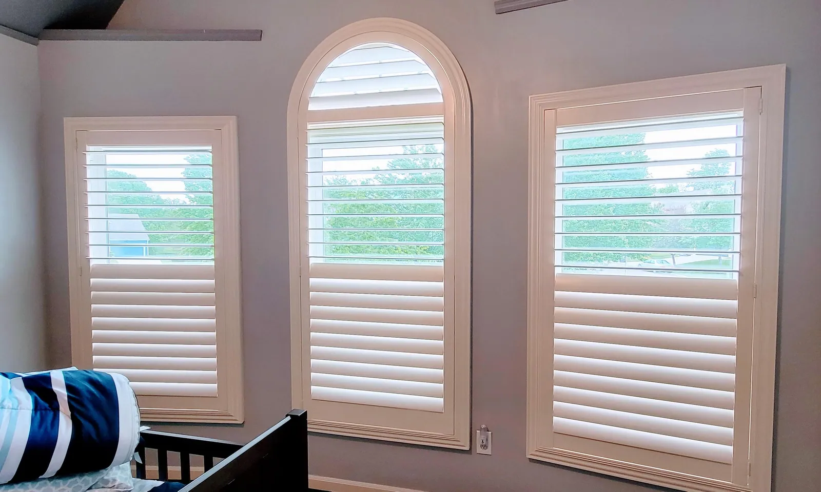 Custom plantation shutters specialty arched in a living room, installed by Solar Shield Blinds