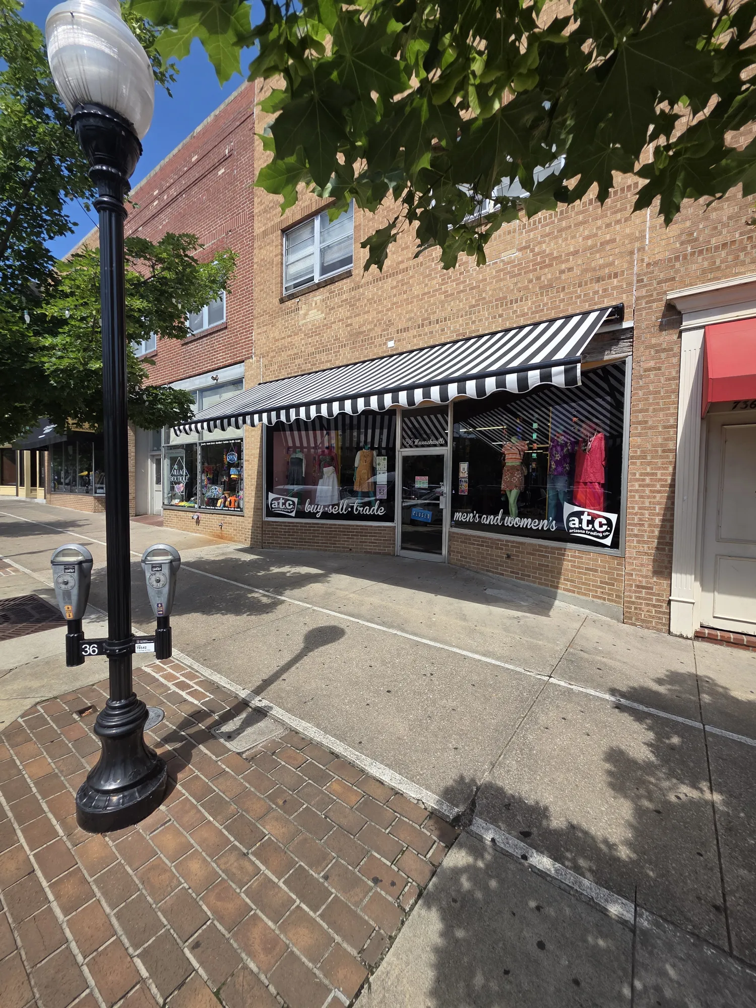 Black and white striped awning over a downtown storefront, installed by Solar Shield Blinds