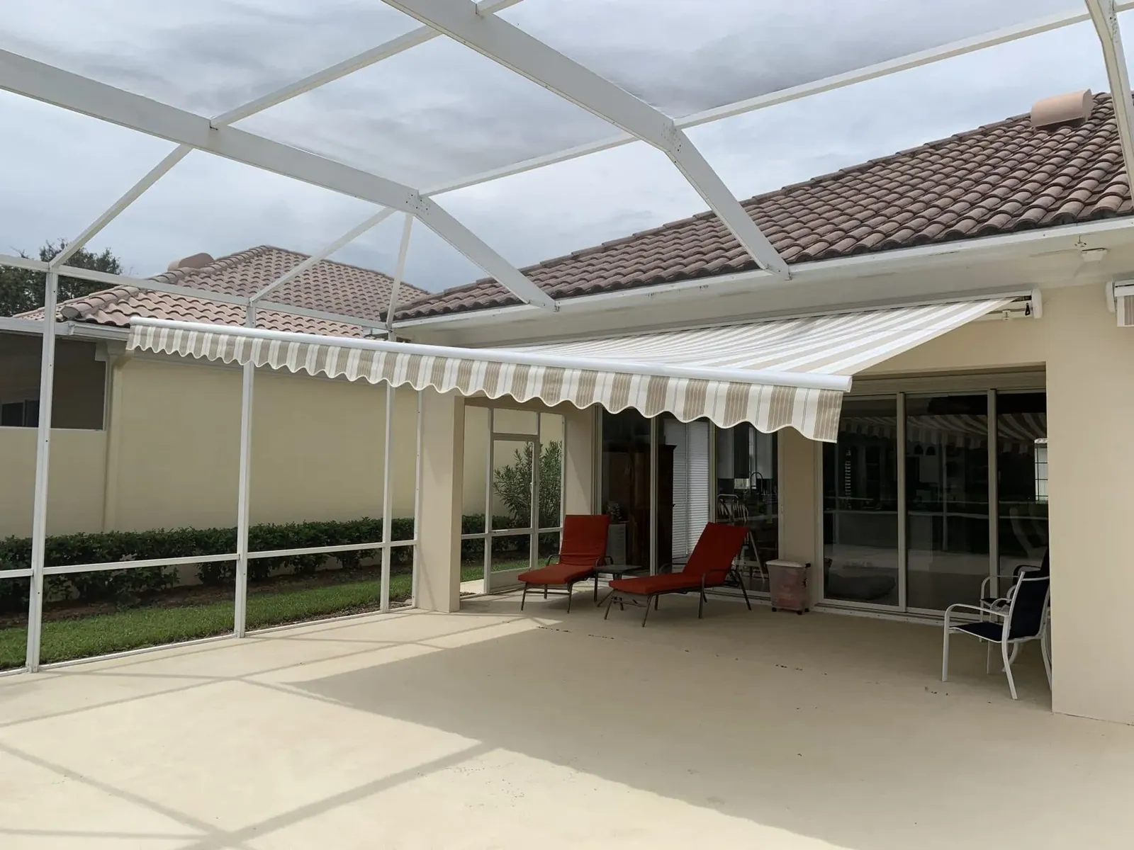 White retractable awning over a patio with chairs underneath, installed by Solar Shield Blinds