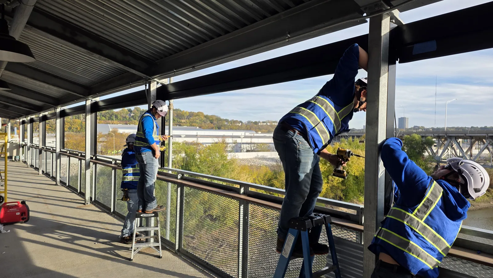 Installers fitting shade headers along the upper deck of the Rock Island Bridge