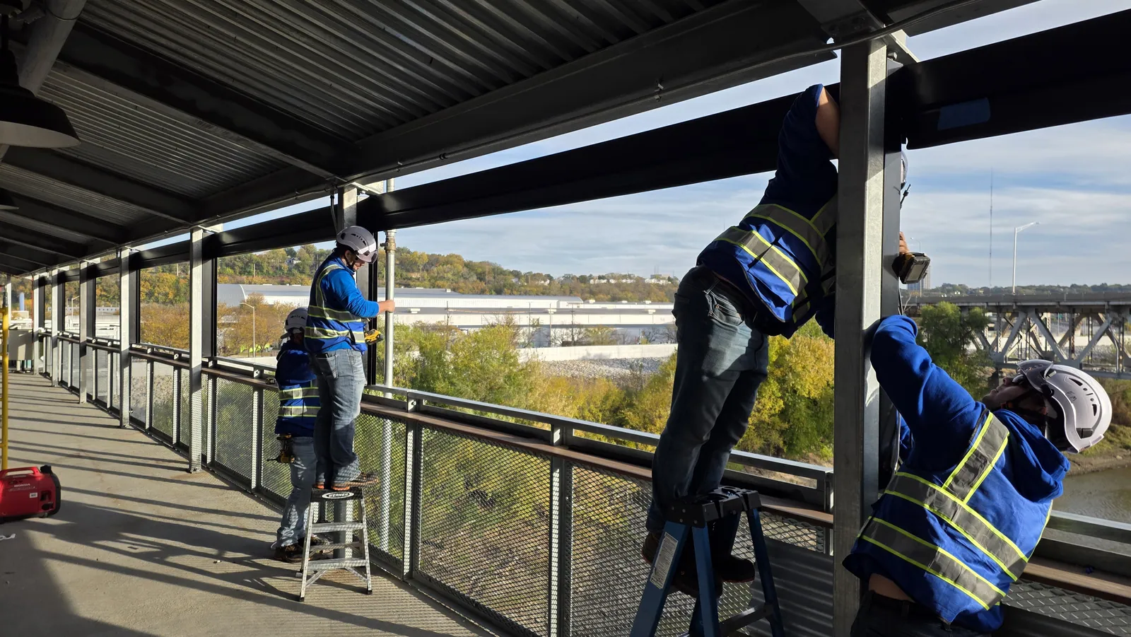 Three Solar Shield Blinds installers setting shade brackets along the upper deck of the Rock Island Bridge