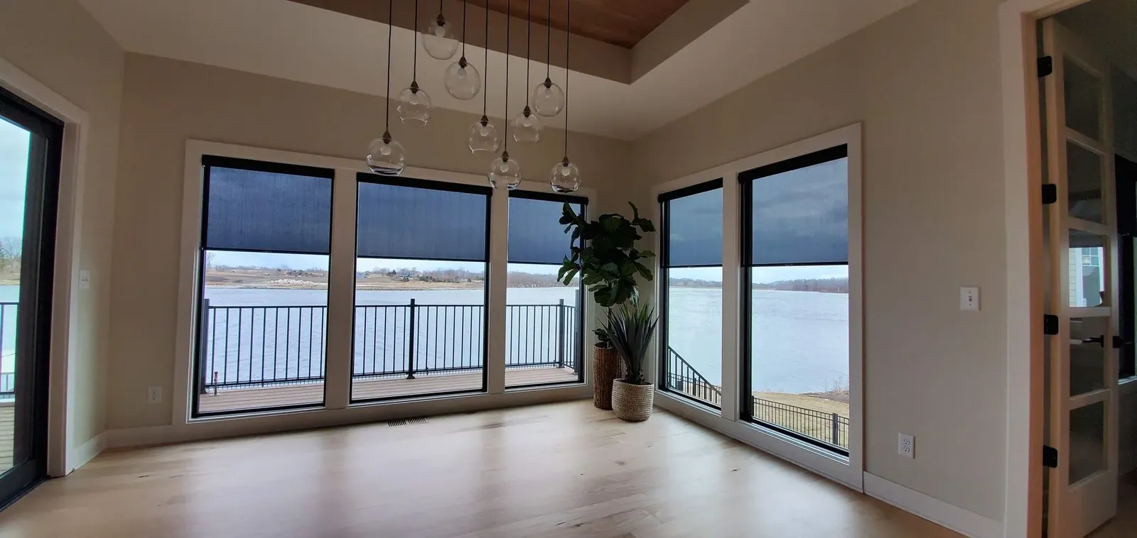 Motorized roller shades lowered halfway across a wall of lake-facing windows
