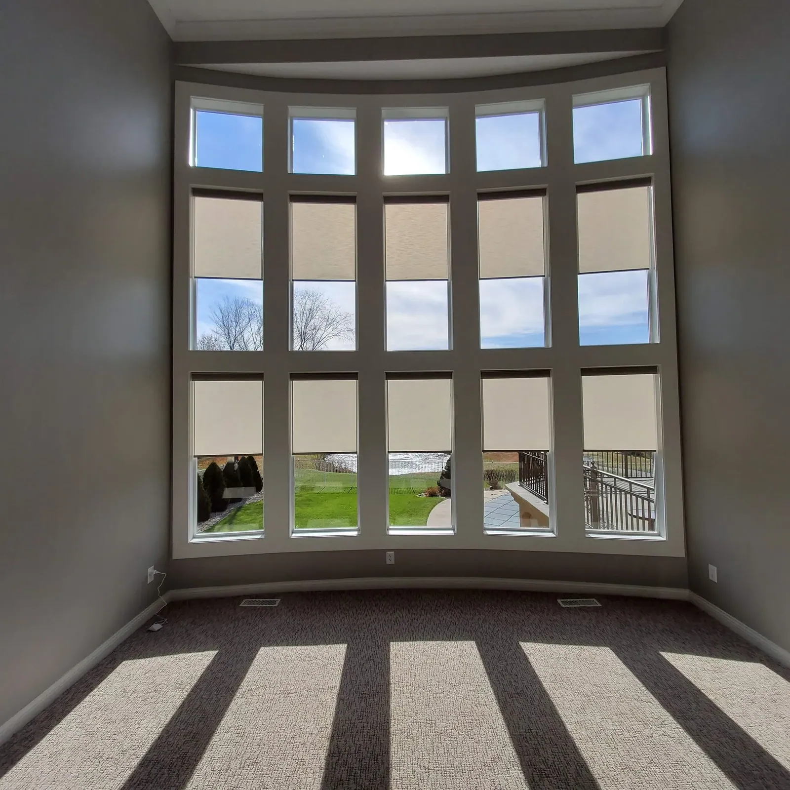 Roller Shades half closed in a living room, a Solar Shield Blinds install