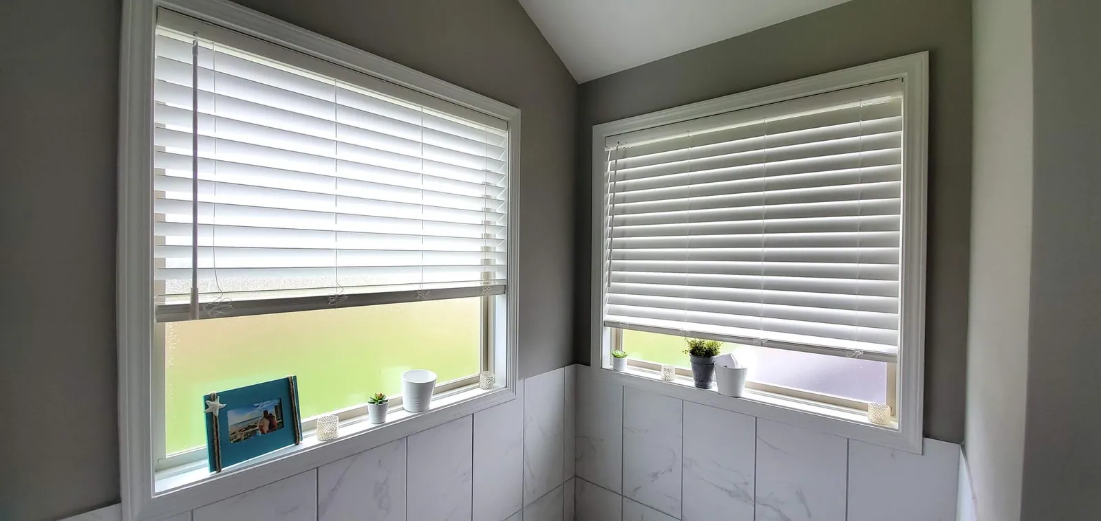 White blinds on two corner windows in a bathroom