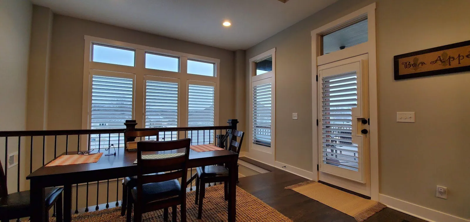 White plantation shutters on a door and windows in a dining area
